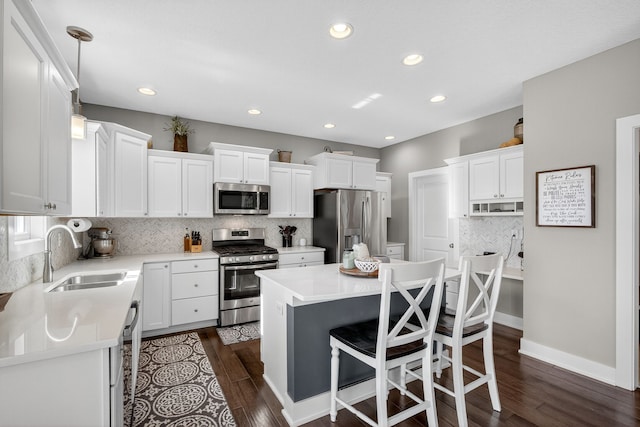 5519 165th St, Urbandale, IA 50323 - kitchen with appliances with stainless steel finishes, tasteful backsplash, white cabinetry, dark wood finished floors, and recessed lighting