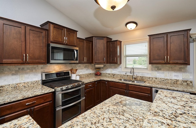 358 S 85th St, West Des Moines, IA 50266 - kitchen with appliances with stainless steel finishes, vaulted ceiling, tasteful backsplash, light stone counters, and dark brown cabinets