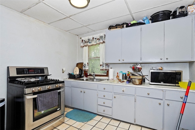 1054 14th St, Des Moines, IA 50314 - kitchen with stainless steel appliances, light countertops, light tile patterned floors, and a drop ceiling