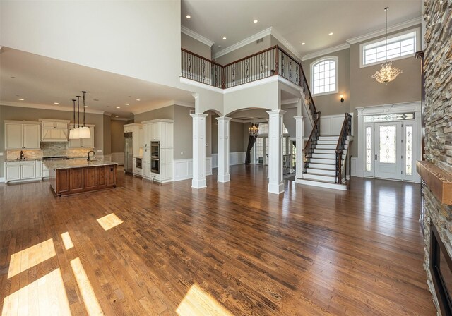 4701 150th St, Urbandale, IA 50323 - unfurnished living room with a high ceiling, stairway, ornate columns, dark wood-style flooring, and recessed lighting