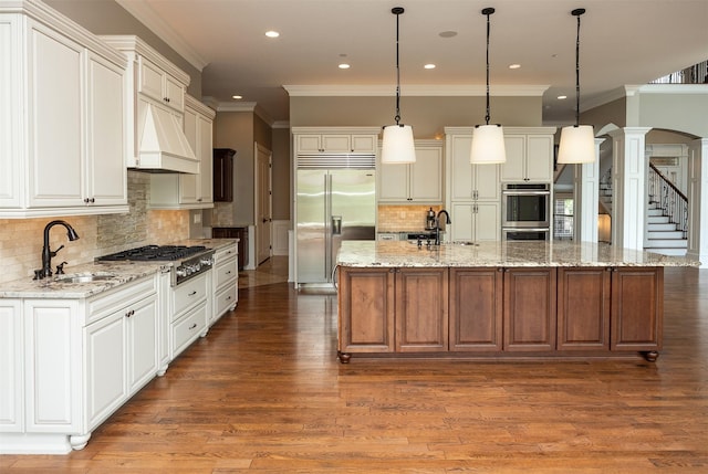 4701 150th St, Urbandale, IA 50323 - kitchen featuring appliances with stainless steel finishes, crown molding, decorative columns, backsplash, and light wood finished floors