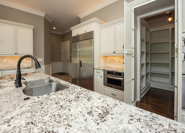 4701 150th St, Urbandale, IA 50323 - kitchen with stainless steel appliances, crown molding, light stone countertops, backsplash, and dark wood finished floors