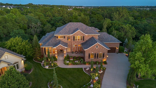 4701 150th St, Urbandale, IA 50323 - view of front of home with a wooded view, brick siding, concrete driveway, a front lawn, and roof with shingles