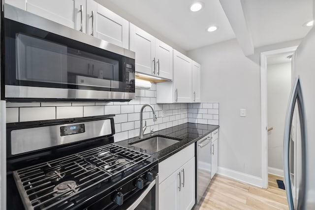 402 S 11th St, Adel, IA 50003 - kitchen with stainless steel appliances, light wood-type flooring, decorative backsplash, dark stone countertops, and white cabinetry