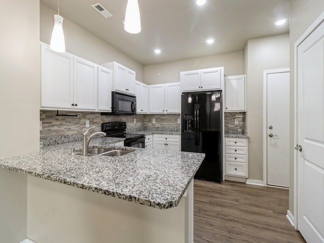 316 SW 6th St Unit 106, Des Moines, IA 50309 - kitchen featuring black appliances, a peninsula, light stone countertops, backsplash, and dark wood finished floors