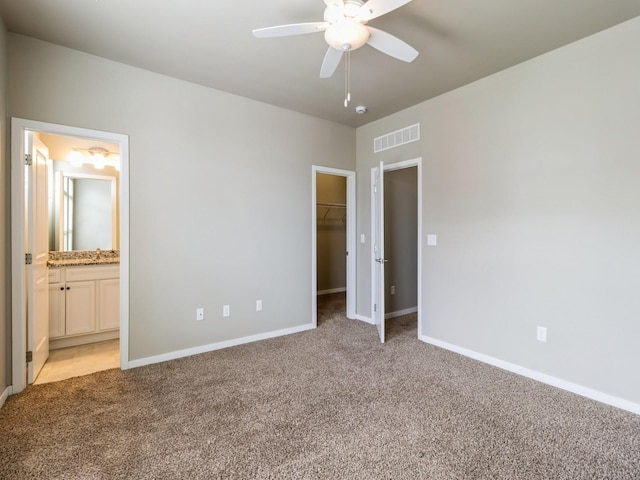 316 SW 6th St Unit 106, Des Moines, IA 50309 - unfurnished bedroom featuring light carpet, a walk in closet, a closet, ensuite bathroom, and ceiling fan