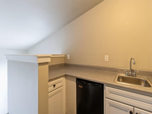 316 SW 6th St Unit 106, Des Moines, IA 50309 - kitchen featuring black dishwasher, white cabinets, and vaulted ceiling