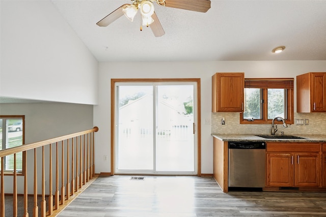 2907 E 43rd St, Des Moines, IA 50317 - kitchen with stainless steel dishwasher, wood finished floors, brown cabinets, backsplash, and a ceiling fan