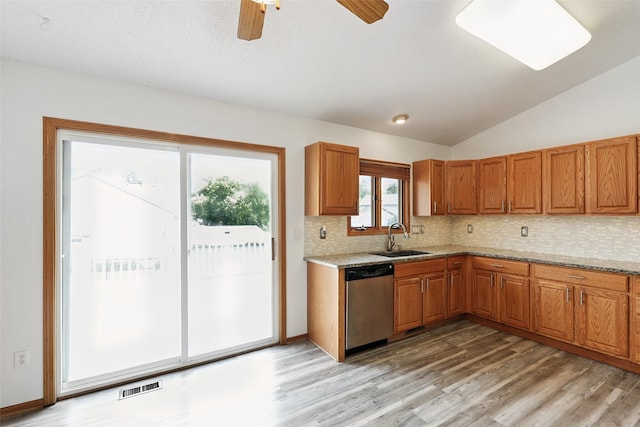 2907 E 43rd St, Des Moines, IA 50317 - kitchen featuring stainless steel dishwasher, brown cabinetry, light wood-style flooring, and lofted ceiling