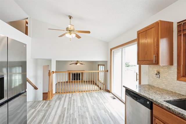 2907 E 43rd St, Des Moines, IA 50317 - kitchen with stainless steel appliances, a ceiling fan, lofted ceiling, brown cabinetry, and light wood-style flooring