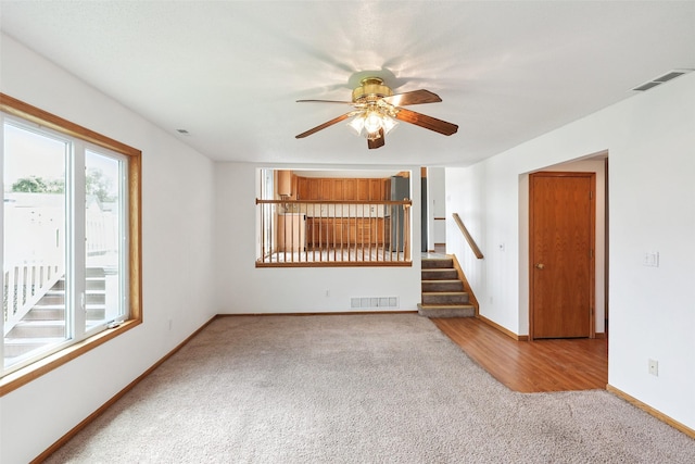 2907 E 43rd St, Des Moines, IA 50317 - unfurnished living room featuring carpet, a ceiling fan, and stairs