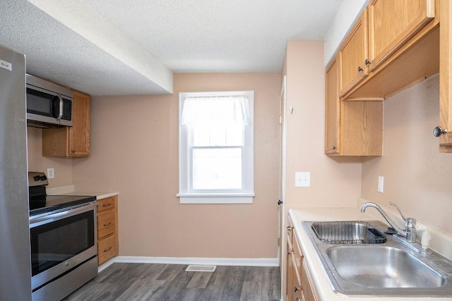 1421 N 4th Ave E, Newton, IA 50208 - kitchen with appliances with stainless steel finishes, dark wood-type flooring, light countertops, and a textured ceiling