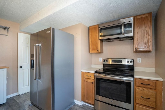 1421 N 4th Ave E, Newton, IA 50208 - kitchen with appliances with stainless steel finishes, brown cabinetry, dark wood-type flooring, a textured ceiling, and light countertops