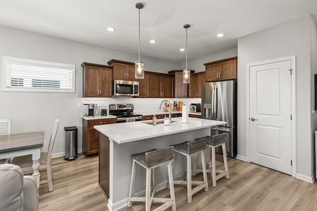 8932 Mockingbird Dr, West Des Moines, IA 50266 - kitchen with stainless steel appliances, light wood-style flooring, light countertops, backsplash, and a kitchen breakfast bar