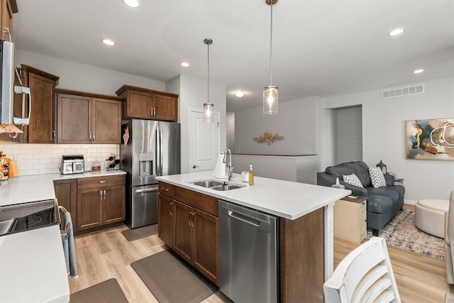 8932 Mockingbird Dr, West Des Moines, IA 50266 - kitchen with appliances with stainless steel finishes, light wood finished floors, backsplash, light countertops, and open floor plan