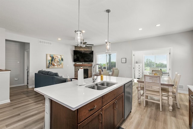8932 Mockingbird Dr, West Des Moines, IA 50266 - kitchen featuring a stone fireplace, light wood-style flooring, dishwasher, open floor plan, and light countertops