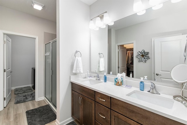 8932 Mockingbird Dr, West Des Moines, IA 50266 - bathroom with a stall shower, a walk in closet, wood finished floors, and double vanity