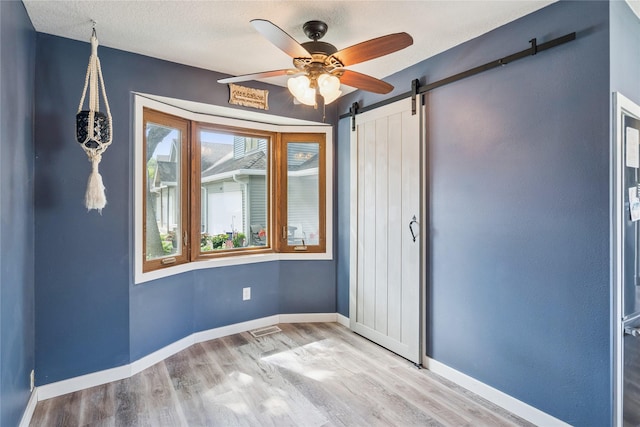 1123 SE Mallard Creek Dr, Ankeny, IA 50021 - spare room featuring a barn door, ceiling fan, wood finished floors, and a textured ceiling