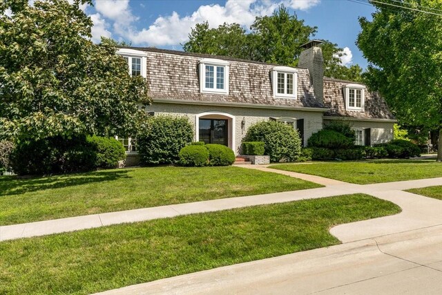 7819 Luin Ln, Windsor Heights, IA 50324 - view of property featuring a front yard, brick siding, a chimney, and mansard roof