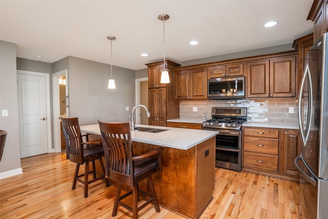 2801 SW Prairie Trail Pkwy, Ankeny, IA 50023 - kitchen featuring appliances with stainless steel finishes, light wood-style floors, tasteful backsplash, an island with sink, and brown cabinets