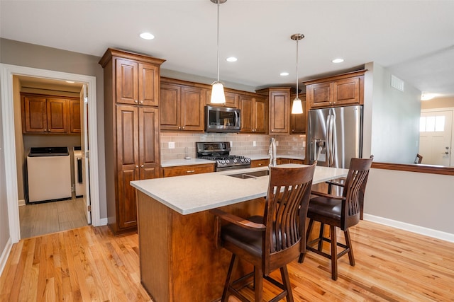 2801 SW Prairie Trail Pkwy, Ankeny, IA 50023 - kitchen featuring appliances with stainless steel finishes, light wood-style flooring, tasteful backsplash, light countertops, and a breakfast bar area
