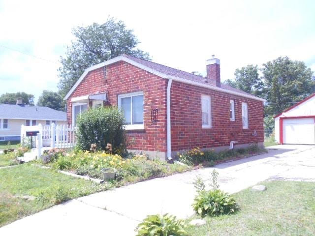 702 Woodbury St, Marshalltown, IA 50158 - view of side of home featuring brick siding, a chimney, an outbuilding, and a detached garage