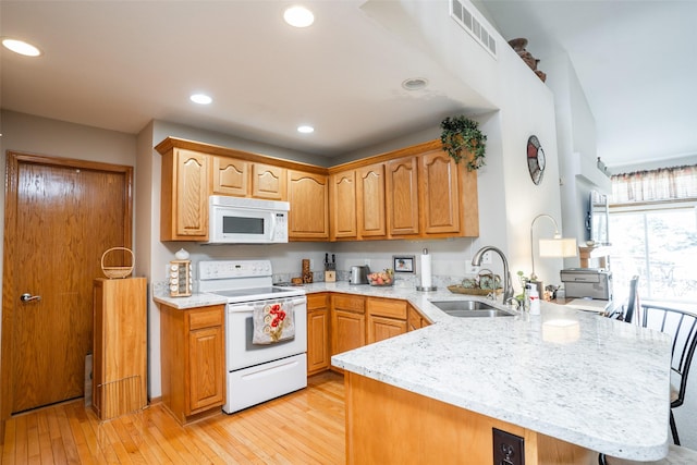 1745 Waters Edge Dr, Pleasant Hill, IA 50327 - kitchen featuring white appliances, a peninsula, light stone counters, light wood-style flooring, and recessed lighting