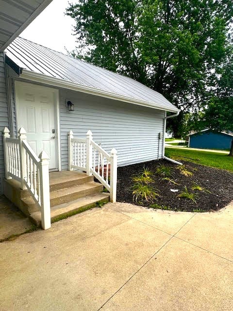 426 N 1st St, Ogden, IA 50212 - view of exterior entry featuring a metal roof, a standing seam roof, and a patio