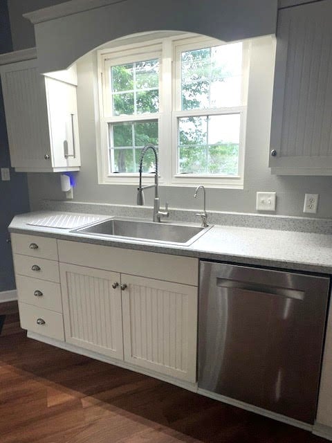 426 N 1st St, Ogden, IA 50212 - kitchen with stainless steel dishwasher, dark wood-style flooring, light countertops, and white cabinets