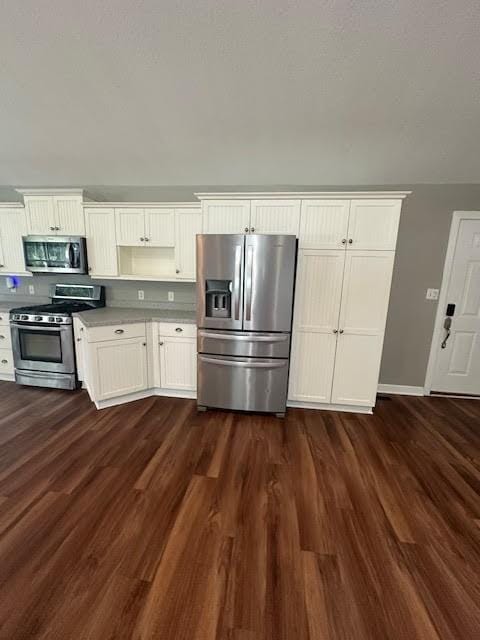 426 N 1st St, Ogden, IA 50212 - kitchen with appliances with stainless steel finishes, dark wood-style flooring, light countertops, and white cabinets