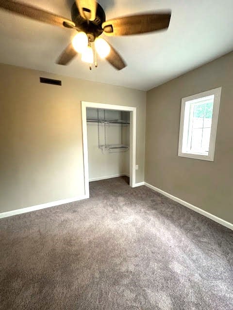 426 N 1st St, Ogden, IA 50212 - unfurnished bedroom featuring dark colored carpet, a closet, and a ceiling fan