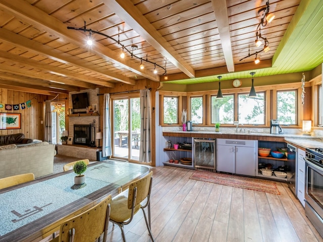 470 Juniper Ave, Kellogg, IA 50135 - kitchen featuring rail lighting, a wood ceiling with exposed beams, appliances with stainless steel finishes, a fireplace, and light wood finished floors
