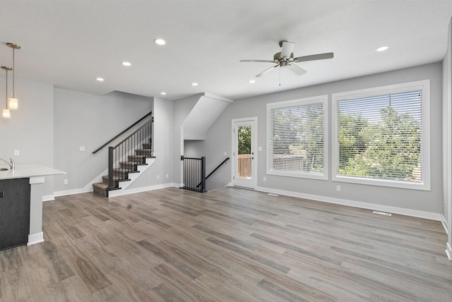 15321 Goldenrod Dr, Urbandale, IA 50323 - unfurnished living room featuring a ceiling fan, recessed lighting, wood finished floors, and stairway