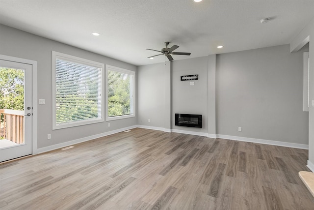 15321 Goldenrod Dr, Urbandale, IA 50323 - unfurnished living room featuring a ceiling fan, light wood-type flooring, recessed lighting, a fireplace, and heating unit