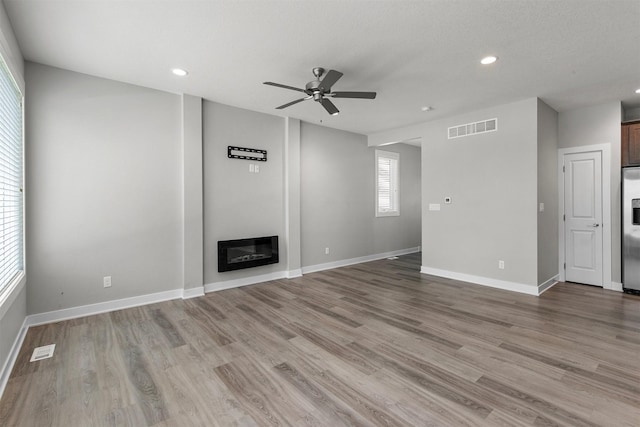 15321 Goldenrod Dr, Urbandale, IA 50323 - unfurnished living room with a ceiling fan, recessed lighting, light wood-style flooring, and a glass covered fireplace