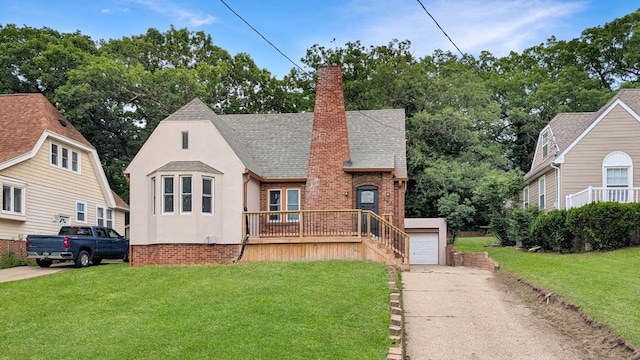 343 58th St, Des Moines, IA 50312 - tudor-style house featuring stucco siding, a front lawn, roof with shingles, and a chimney