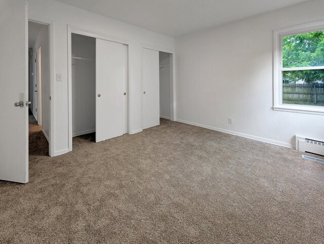 1410 Thomas St, Redfield, IA 50233 - unfurnished bedroom with two closets, carpet floors, and baseboard heating