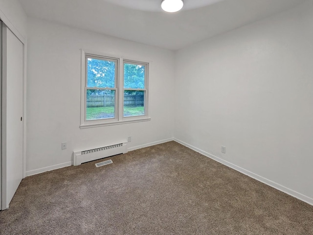 1410 Thomas St, Redfield, IA 50233 - unfurnished bedroom featuring a baseboard heating unit, dark carpet, and a closet