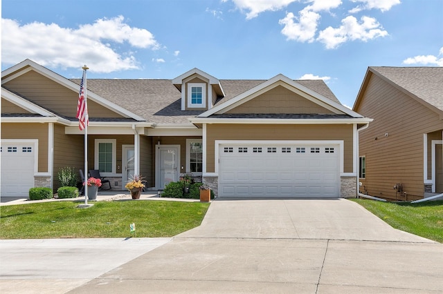 1592 SE Blackthorne Dr, Waukee, IA 50263 - craftsman-style home with stone siding, driveway, a front lawn, a garage, and roof with shingles