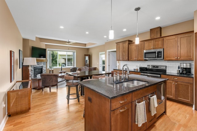 1592 SE Blackthorne Dr, Waukee, IA 50263 - kitchen featuring stainless steel appliances, brown cabinets, light wood-style floors, and recessed lighting
