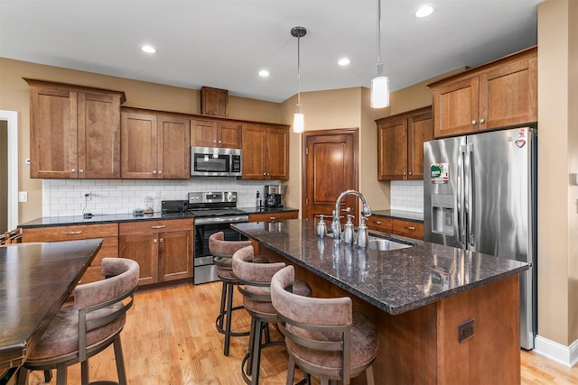 1592 SE Blackthorne Dr, Waukee, IA 50263 - kitchen featuring appliances with stainless steel finishes, light wood finished floors, brown cabinets, and recessed lighting