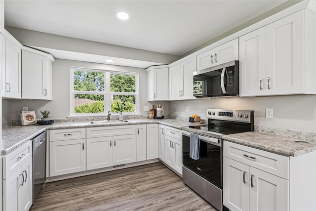 8066 Pilmer Dr, Des Moines, IA 50320 - kitchen featuring appliances with stainless steel finishes, recessed lighting, white cabinetry, light wood finished floors, and light stone counters