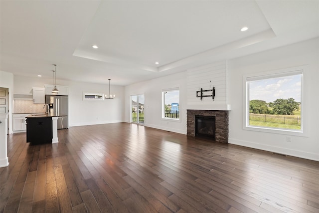1824 Bentley Ct, Norwalk, IA 50211 - unfurnished living room with a raised ceiling, dark wood finished floors, recessed lighting, a stone fireplace, and a chandelier