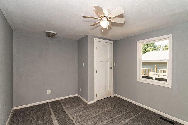 1718 Otley Ave, Perry, IA 50220 - unfurnished room featuring a ceiling fan, dark colored carpet, and a textured ceiling
