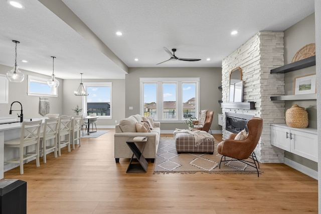 17736 Hammontree Dr, Clive, IA 50325 - living room with a stone fireplace, light wood-style floors, ceiling fan, and recessed lighting