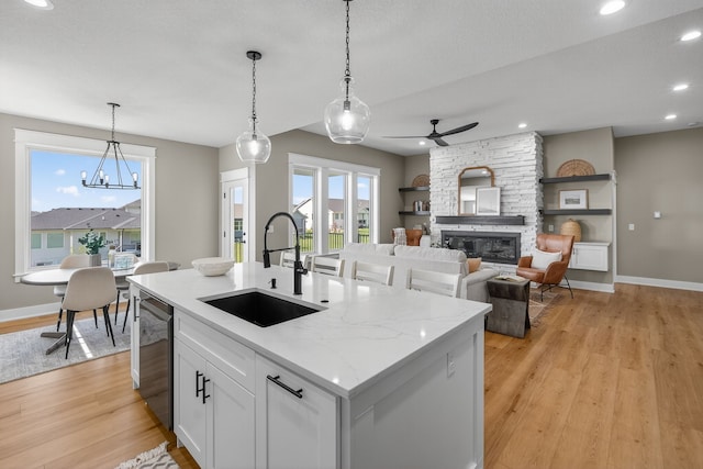 17736 Hammontree Dr, Clive, IA 50325 - kitchen with light wood-type flooring, stainless steel dishwasher, decorative light fixtures, white cabinets, and a fireplace