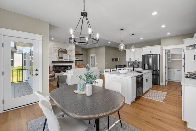 17736 Hammontree Dr, Clive, IA 50325 - dining room featuring light wood finished floors, recessed lighting, a fireplace, and a chandelier