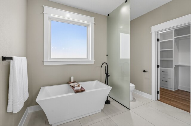 17736 Hammontree Dr, Clive, IA 50325 - bathroom featuring a soaking tub, tile patterned flooring, and a walk in closet