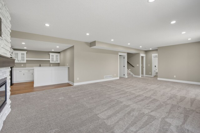 17736 Hammontree Dr, Clive, IA 50325 - unfurnished living room featuring light carpet, a fireplace, stairs, recessed lighting, and bar with sink