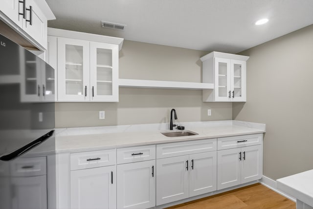 17736 Hammontree Dr, Clive, IA 50325 - kitchen with white cabinets, light stone counters, light wood-style floors, glass insert cabinets, and open shelves